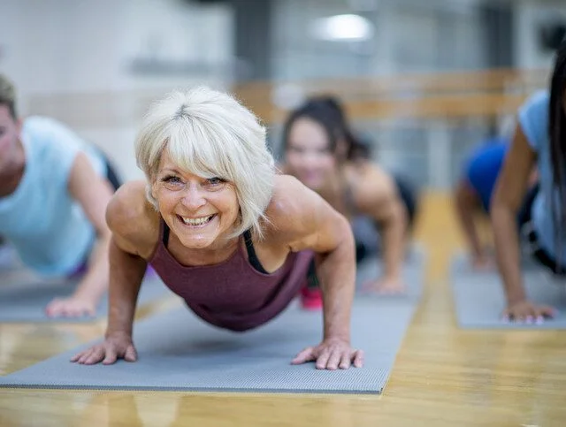 Senior Woman in Fitness Class in a Plank Pose Smiling stock photo