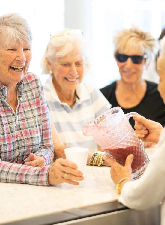 group of senior women smile while being served healthy smoothies