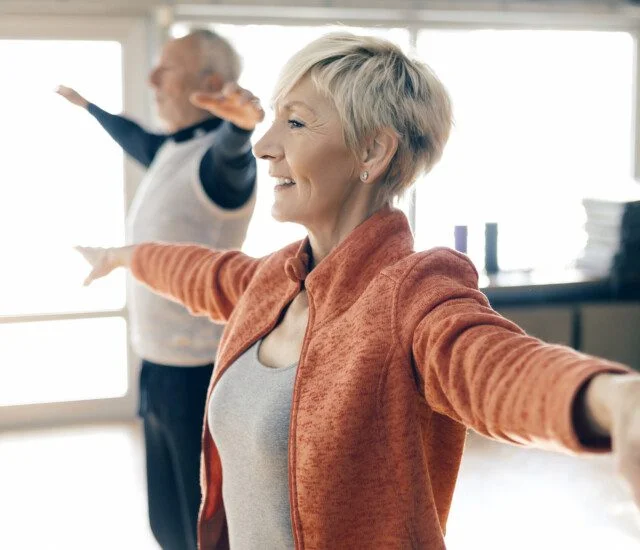 Active seniors in fitness class stretching arms