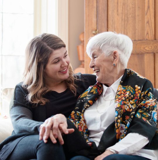 older woman and younger woman on sofa looking at each othwr