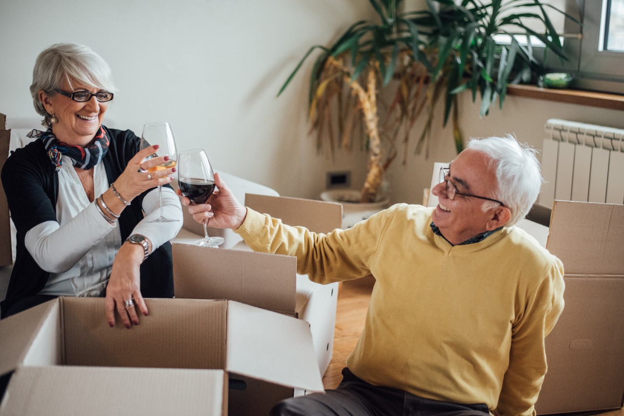 Senior couple drinking wine after unpacking moving boxes