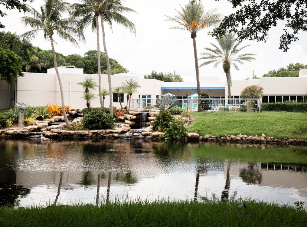 small waterfall, body of water, pine trees, and landscaping at Harbour's Edge Senior Living Community