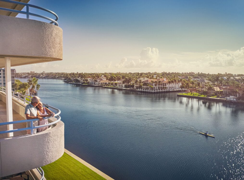 senior couple lean against each other and enjoy the stunning waterfront views from the restaurant balcony at Harbour's Edge