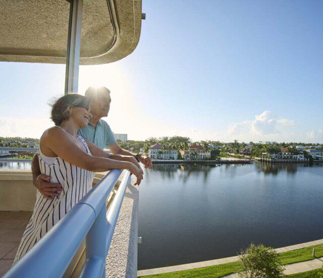 senior couple lean against each other and enjoy the stunning waterfront views from the restaurant balcony at Harbour's Edge
