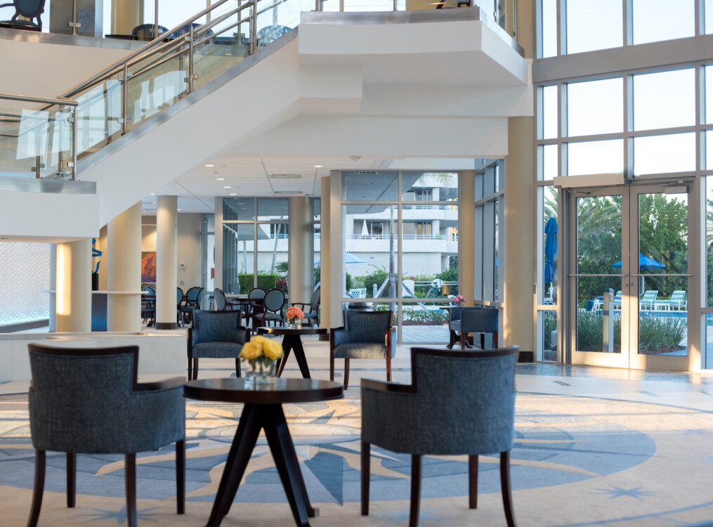 elegant and contemporary lobby area with floor-to-ceiling glass walls and two sets of chairs at Harbour's Edge