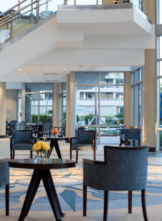 elegant and contemporary lobby area with floor-to-ceiling glass walls and two sets of chairs at Harbour's Edge