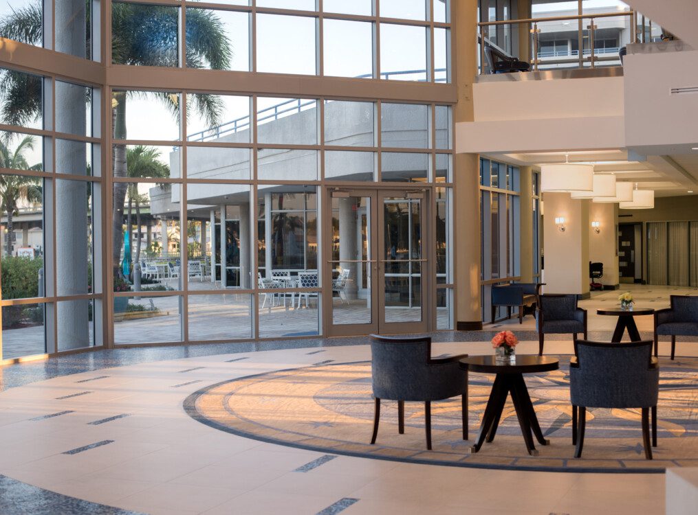 elegant and contemporary lobby area with floor-to-ceiling glass walls and two sets of chairs at Harbour's Edge Senior Living Community