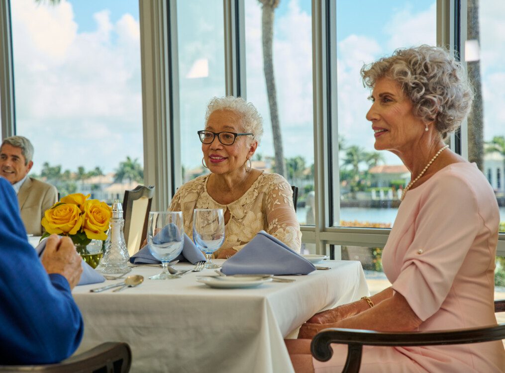 close up of seniors smiling and conversing together over dinner and wine in an elegant dining space at Harbour's Edge