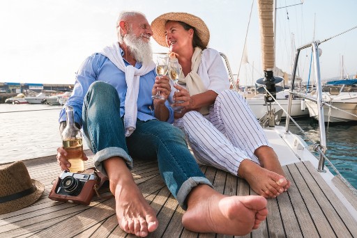senior couple toasting as they sit on a sailboat