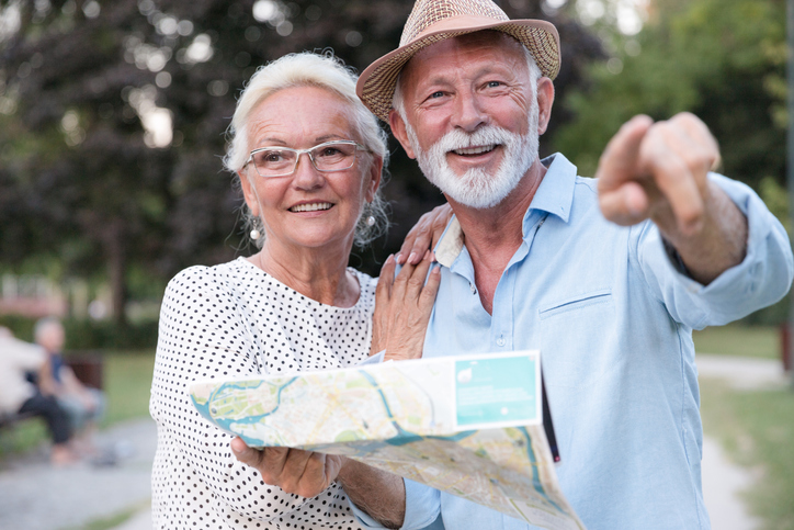 Smiling mature woman hugging a man pointing direction