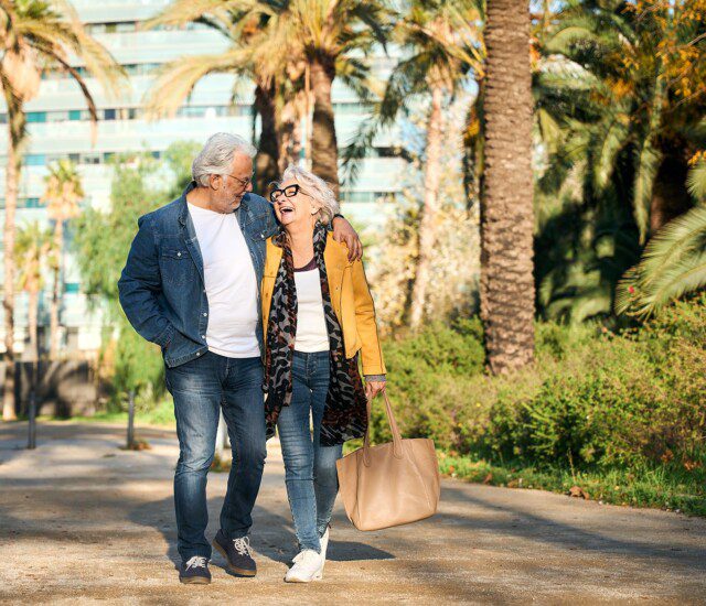2 Seniors waling on pathway with palm trees
