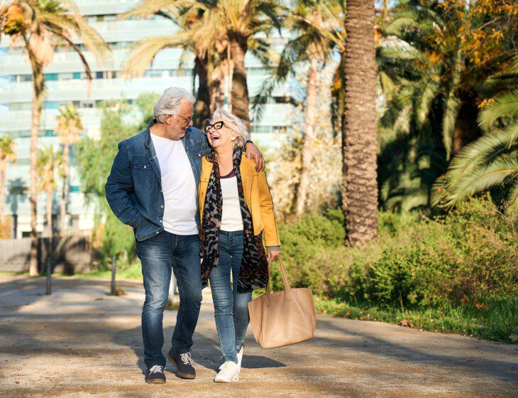 2 Seniors waling on pathway with palm trees